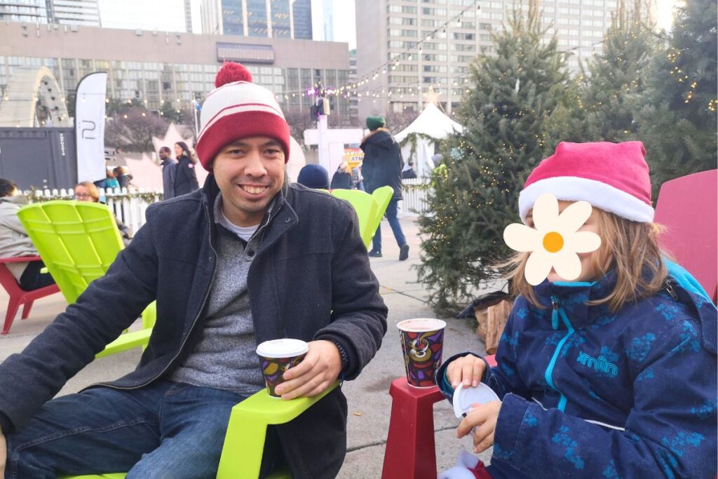 my husband and daughter enjoying a hot chocolate at Nathan Phillips Square in Toronto