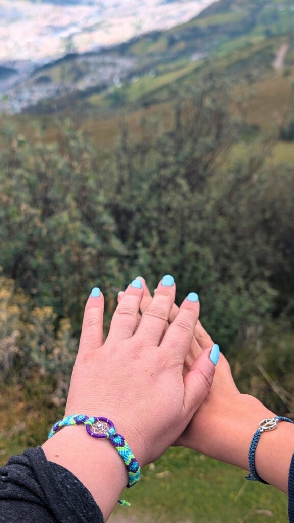 Friendship bracelets made in Ecuador, on wrists with mountains in the background