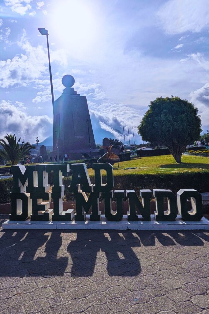 Mitad del Mundo sign with the iconic Middle of the World monument behind it
