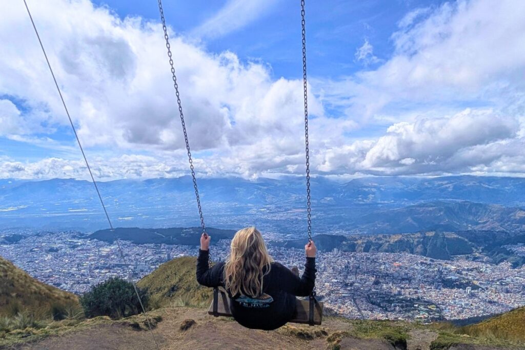 A woman swinging on the swing at the edge of the clouds in Quito