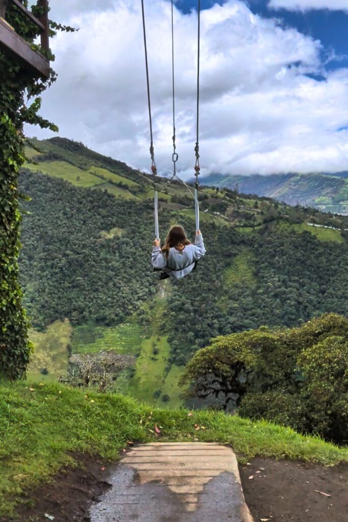a girl swinging on the swing at the end of the world in Baños, Ecuador