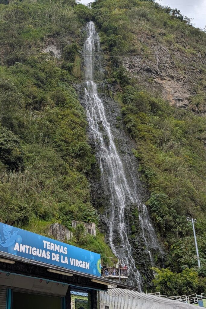 A view of Termas de la Virgen sign in front of the Cascada de la Virgen waterfall in Baños, Ecuador